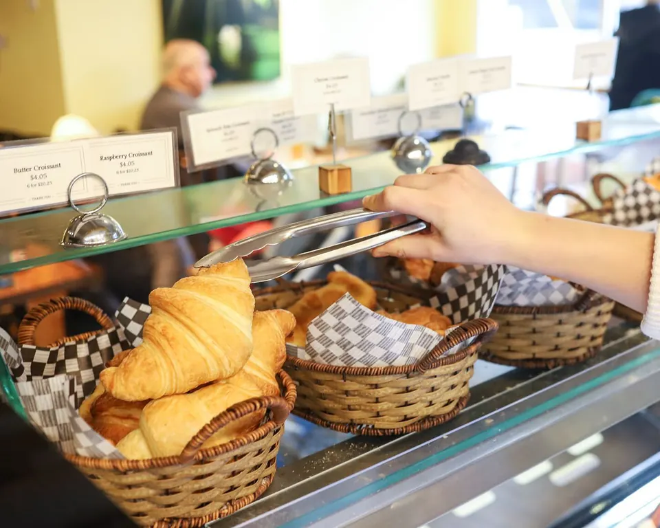 A butter croissant being lifted from a basket at Bubby Rose’s