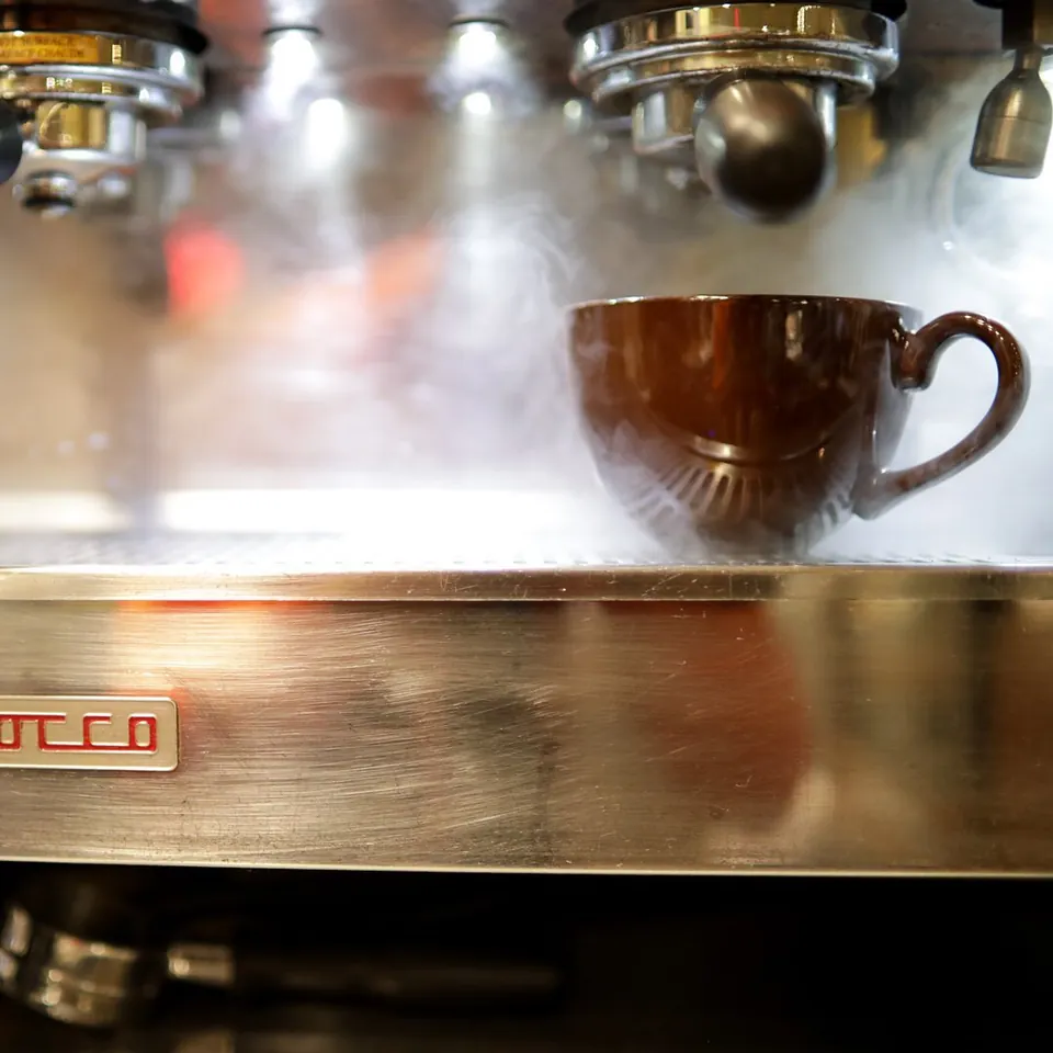 A brown coffee cup beneath the espresso machine